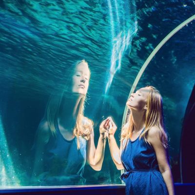 young-woman-looking-at-fish-in-tunnel-aquarium-min
